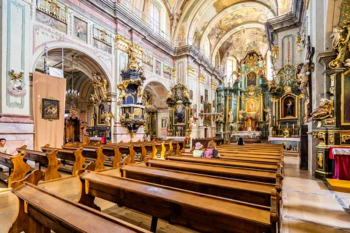 Widok z nawy bocznej na ławy, ambonę oraz ołtarz główny franciszkańskiej świątyni w Przemyślu.