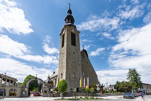 Fronton limanowskiego sanktuarium z wysuniętą wieżą zegarową oraz bramą wejściową.