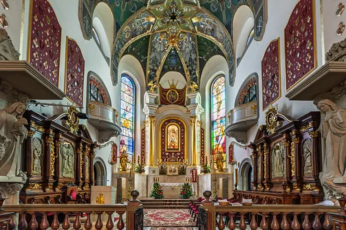 Ołtarz główny sanktuarium w Limanowej z nastawą, witrażami oraz drewnianymi stallami.