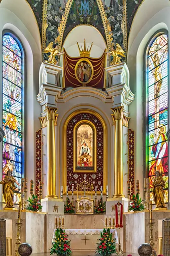 Ołtarz główny limanowskiej bazyliki z figurą Piety w otoczeniu witraży.