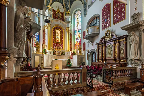 Prezbiterium świątyni w Limanowej z kamienną balustradą i drewnianymi stallami.