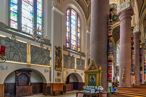 Ściana boczna limanowskiej bazyliki z wysokimi witrażami oraz płaskorzeźbami.