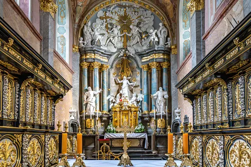 Barokowy ołtarz główny ujęty po bokach rzeźbionymi stallami w prezbiterium jędrzejowskiej bazyliki.