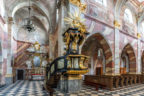 Czarno-złota barokowa ambona na filarze nawy głównej świątyni cysterskiej w Jędrzejowie.