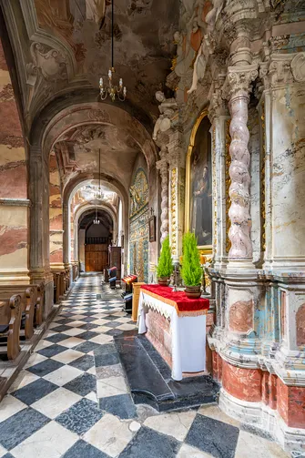 Nawa boczna z architekturą retabulum i polichromowanymi filarami kościoła cystersów w Jędrzejowie.