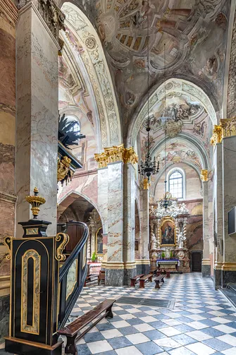 Ambona na tle polichromowanych filarów i posadzki w kościele cystersów w Jędrzejowie.