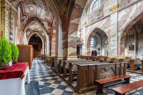 Drewniane ławki i profilowane filary w nawie bocznej świątyni w Jędrzejowie.
