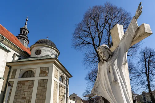 Detal rzeźbiarski z kopułą kaplicy żywieckiej świątyni widoczną w tle.