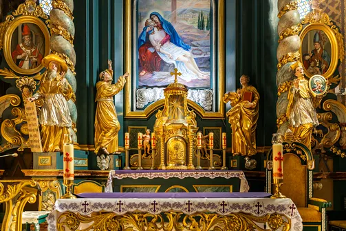 Barokowy ołtarz główny żywieckiej konkatedry z rzeźbami świętych i pozłacanym tabernakulum.