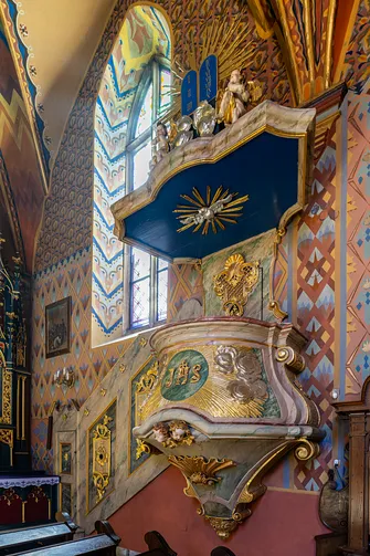 Barokowa ambona ze złoconymi zdobieniami przy ścianie nawy w Żywcu.