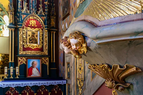 Rzeźbiony detal główki anioła przy korpusie ambony w kościele w Żywcu.