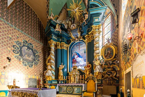 Barokowy ołtarz główny na tle barwnych polichromii żywieckiej fary.