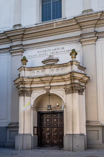 Detal architektoniczny głównego portalu wejściowego z kamiennym obramowaniem w fasadzie.