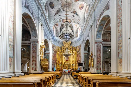 Wnętrze nawy głównej skierowane ku dekoracyjnemu ołtarzowi w sanktuarium Matki Bożej Trybunalskiej.