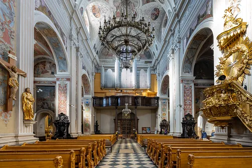 Nawa główna sanktuarium z drewnianymi ławkami, amboną i prospektem organowym na chórze.