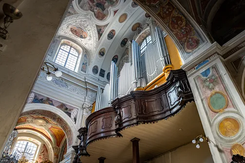 Drewniana empora chórowa z prospektem organowym w barokowym wnętrzu kościoła.